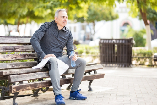 Male walker taking a rest on park bench