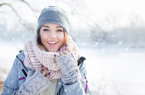 Woman in warm clothing smiling in the snow