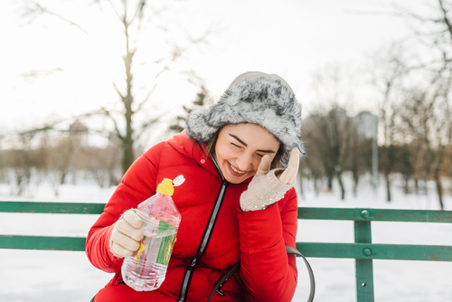 Woman drinking a bottle of water in a snowy park