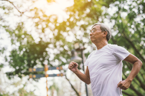 Senior man jogging in a sunny park