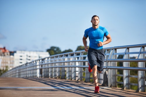 Athletic man jogging over bridge