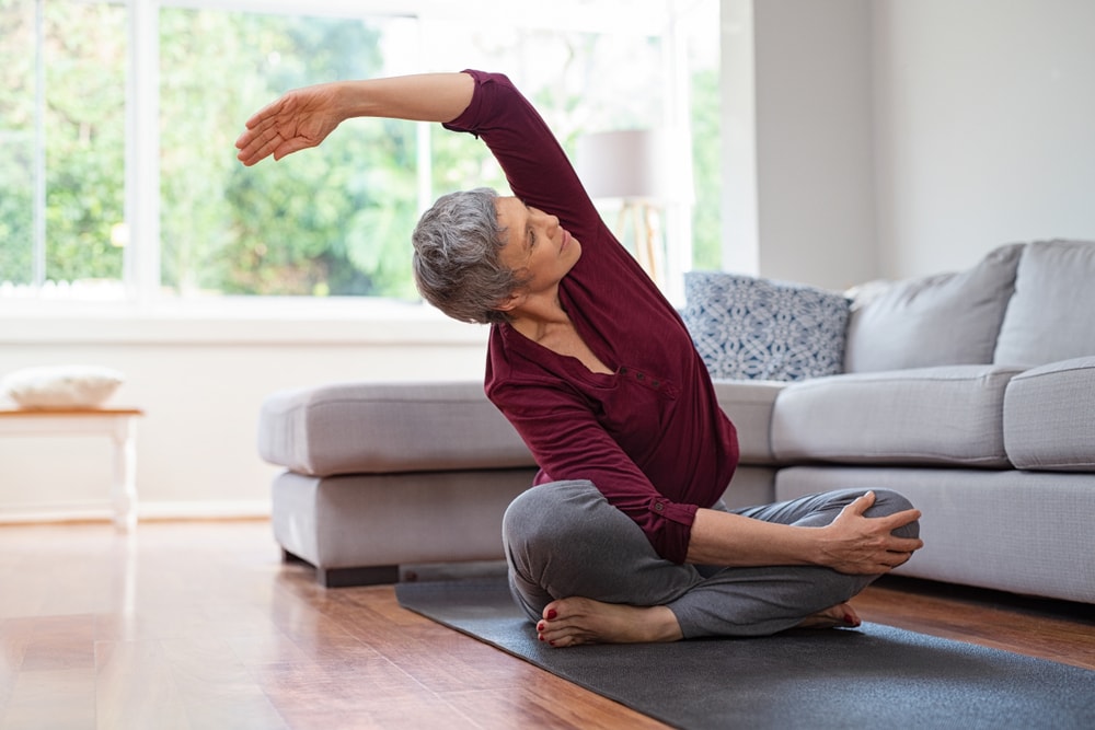 Senior woman doing yoga at home in living room