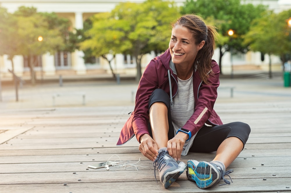 Fit woman sitting and tying shoes during a walk
