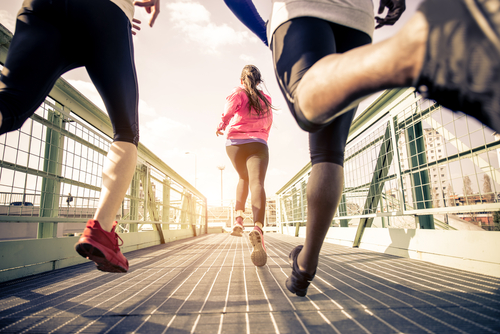 Runners on a bridge focused on their shoes