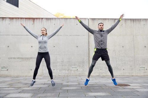 Couple doing jumping jacks outside