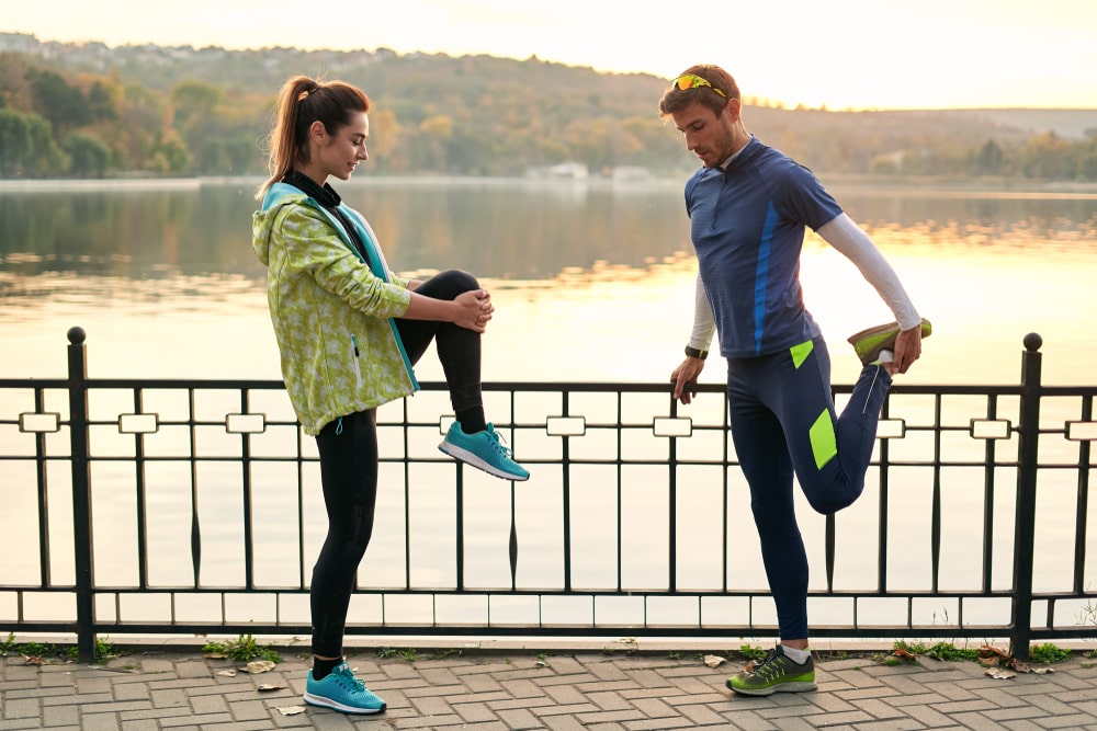 Fit couple stretching before walk near lake