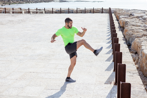 Man doing leg swings near the ocean