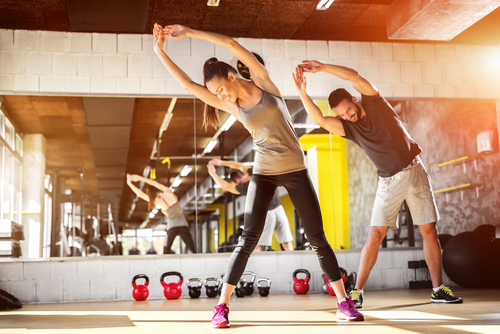Man and woman doing overhead stretches