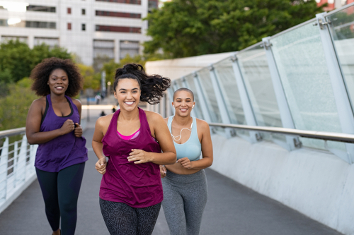 3 women power walking on a city bridge