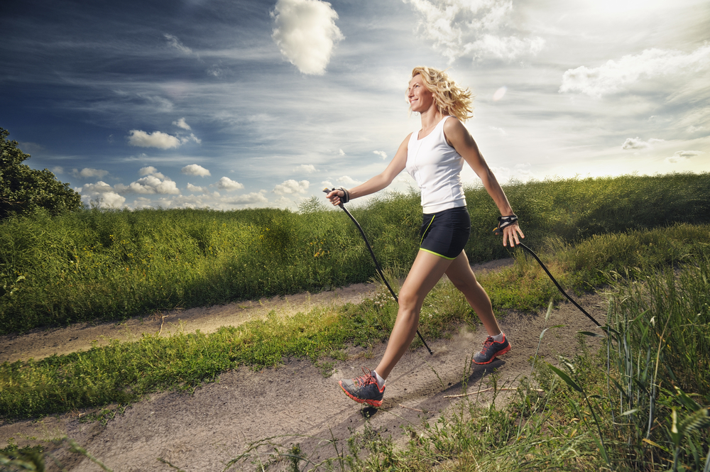 Woman Nordic walking on a green countryside path
