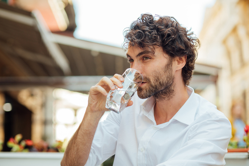 Man drinking water at an outdoor cafe