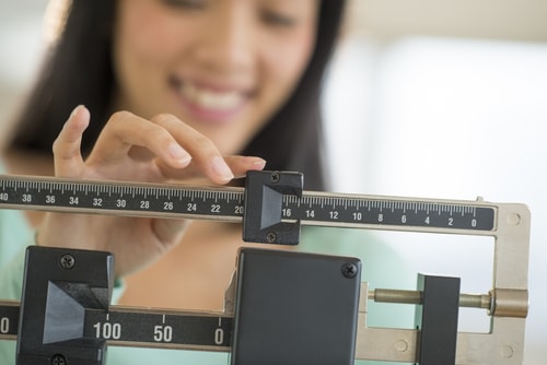Woman checking scale - weight control concept