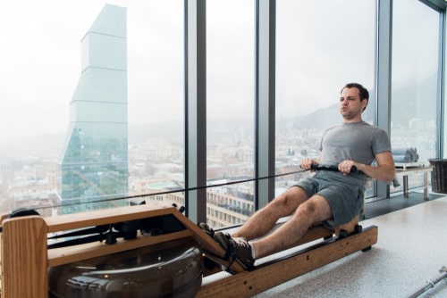 Man in high-rise using rowing machine