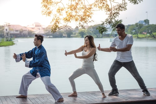 group doing tai chi next to lake