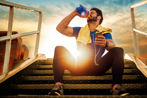 Athlete drinking water during a walk at sunset