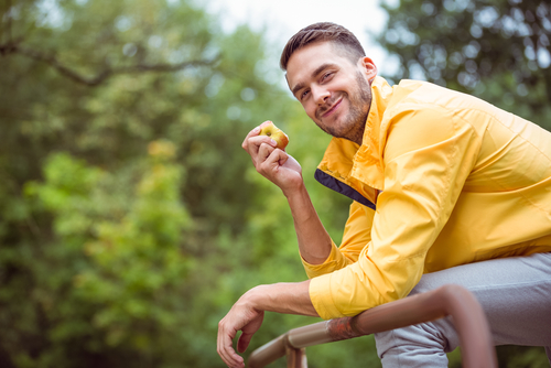 Man sitting on park bench eating an apple snack