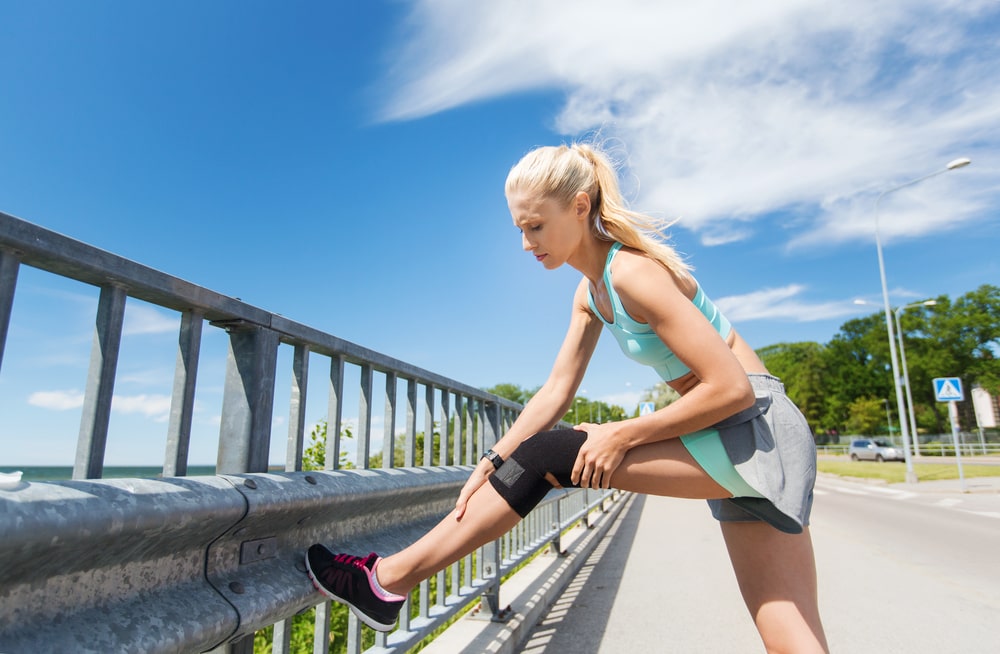 Female athlete adjusting knee brace during a walk