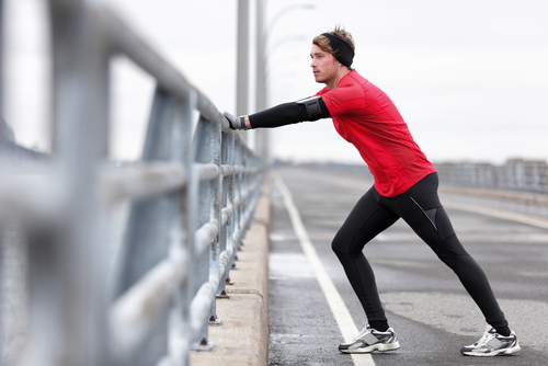 Man stretching legs on bridge during a walk