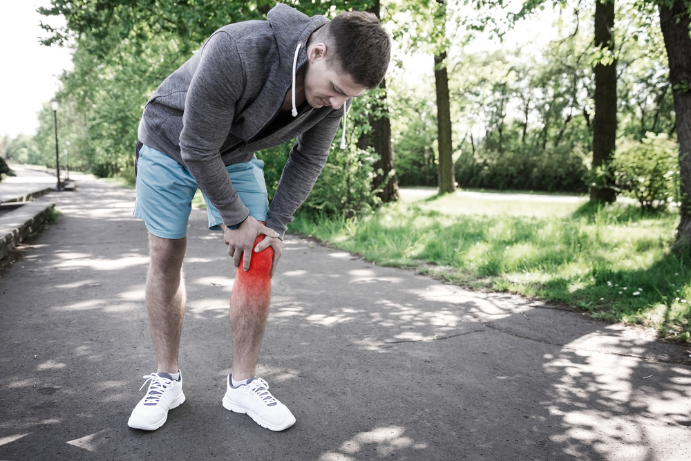 Man holding sore knee after jogging