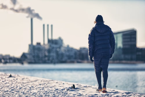 Man walking in front of polluting factory with smoke