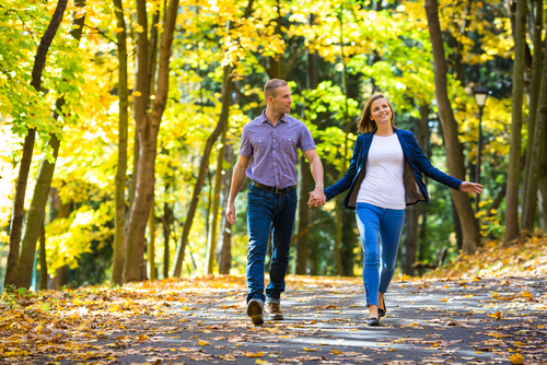 Couple walking in park with autumn leaves