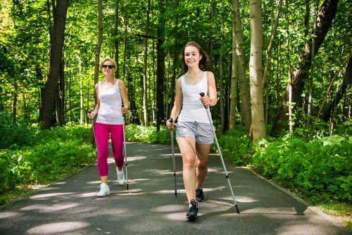 Women power walking with poles in the park