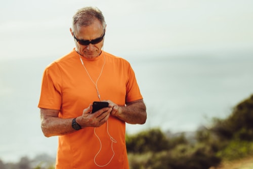 Athletic senior man checking phone during exercise
