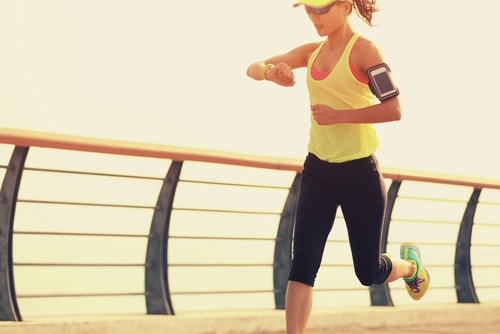Sporty woman checking watch while running