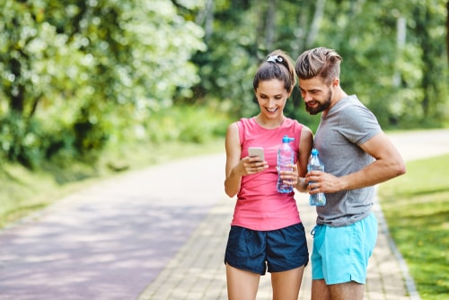 Couple on a fitness walk checking smartphone