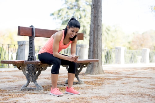 Jogger checking phone on park bench