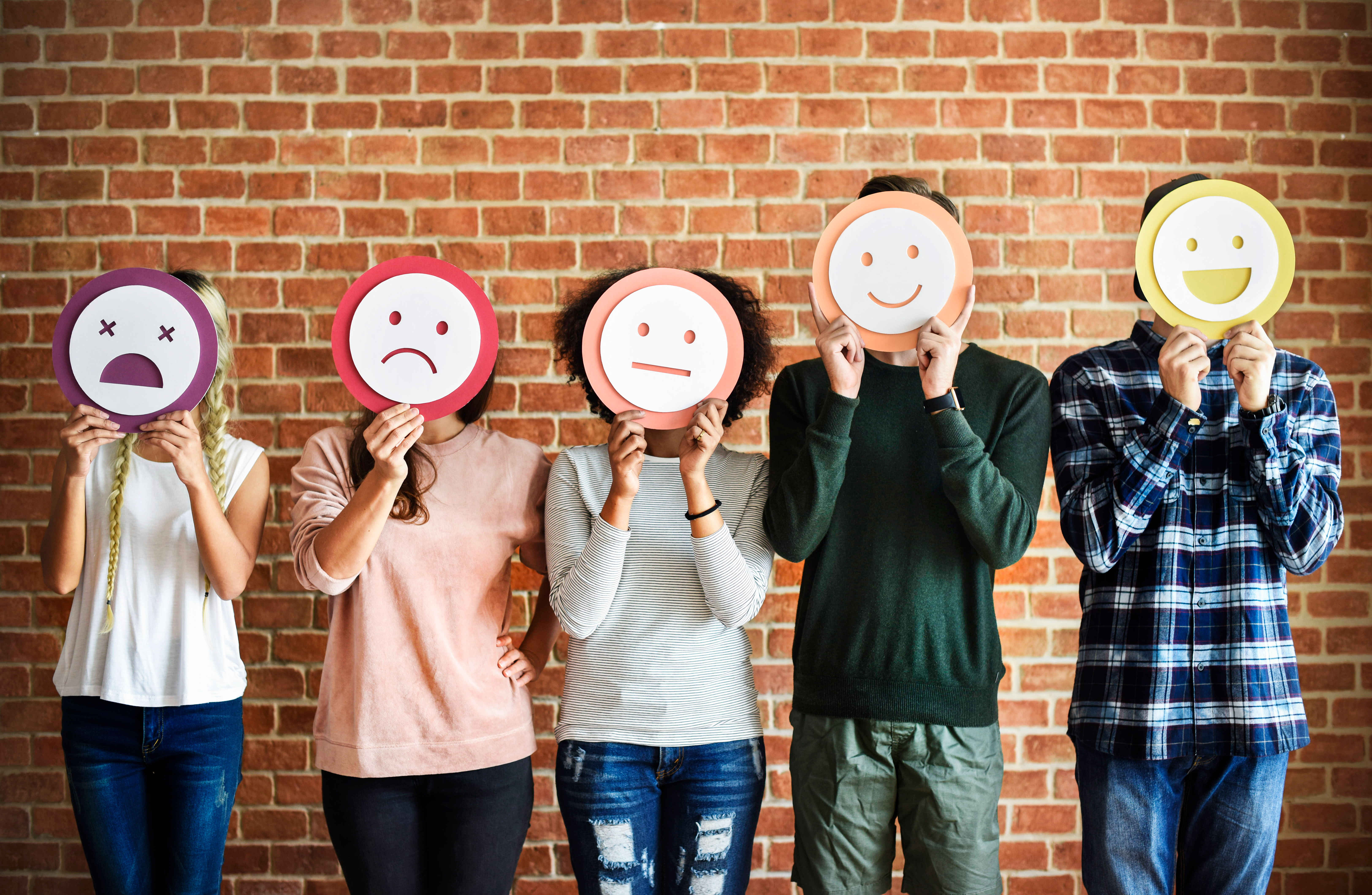 group of adults holding cartoon faces of moods over their faces