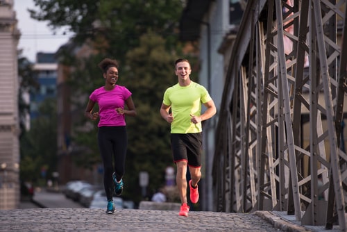 Man and woman running together on a bridge