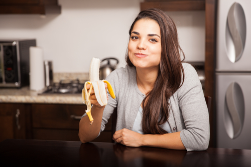 Smiling woman eating a banana as a snack