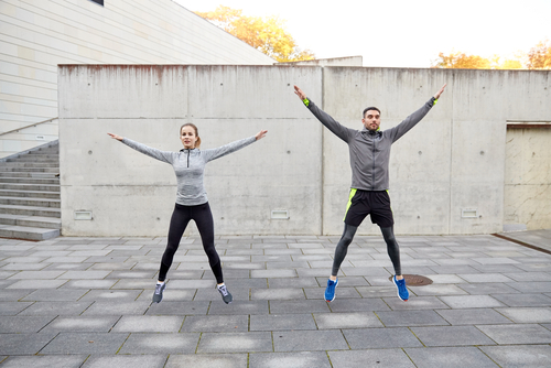 Couple doing jumping jacks outside