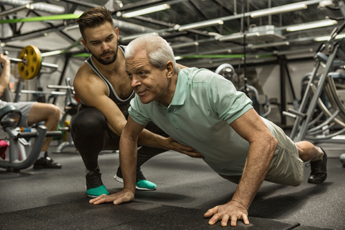 Coach helping an older man do perfect pushups