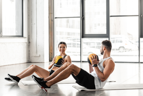 Couple using yoga mat and medicine balls