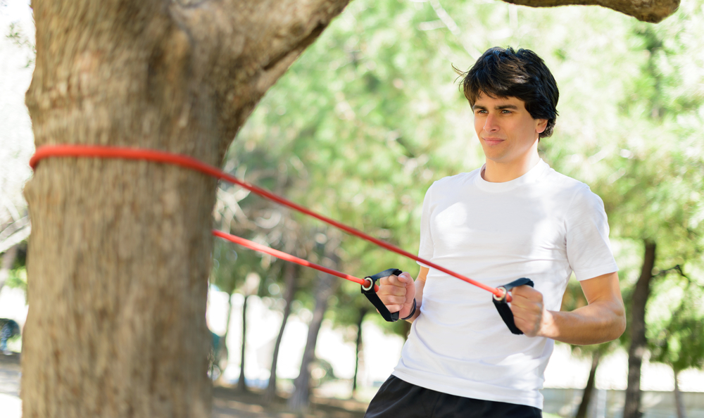 Man exercising with a resistance band in the park