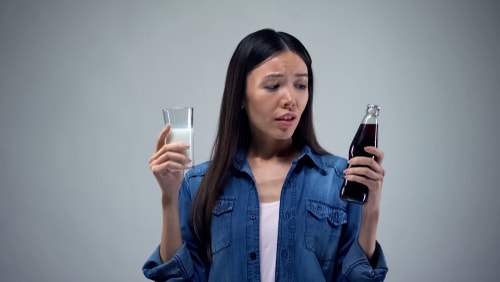 Woman choosing between soda and milk
