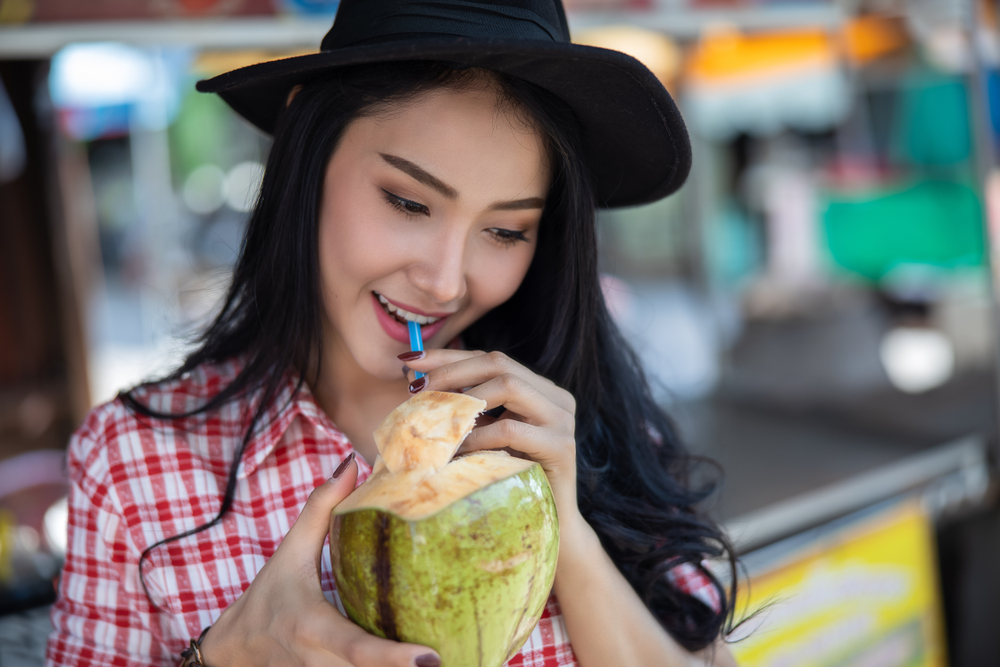 Woman drinking coconut water from a coconut