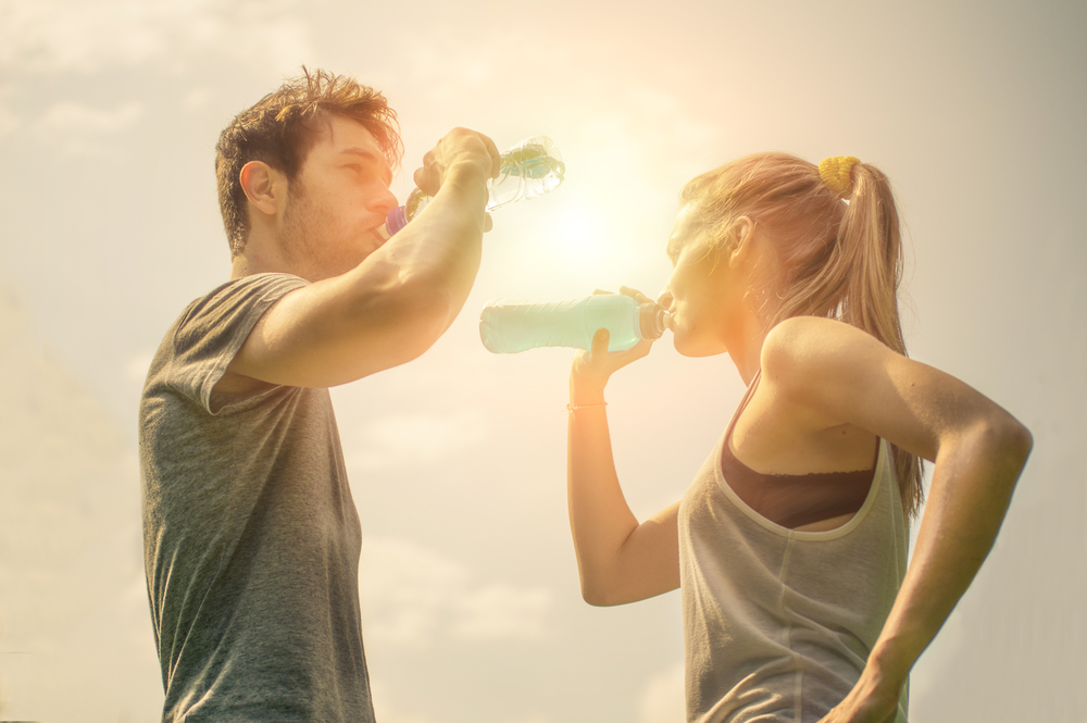 Man and woman drinking water while walking