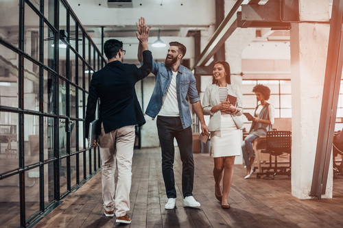 Young workers high fiving while walking