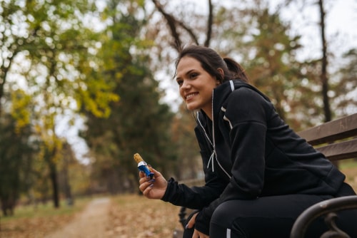 Woman eating energy bar on park bench