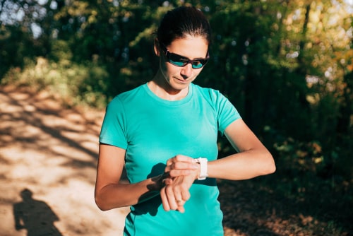 Woman checking watch on a walk in the park