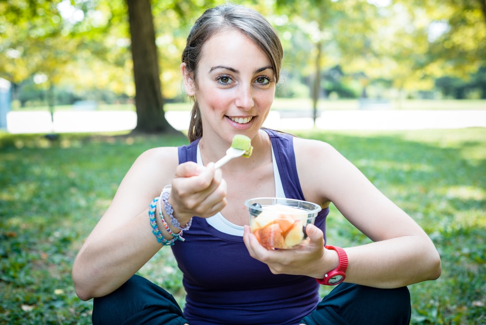 Sporty woman eating healthy fruit in the park