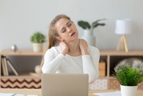 Woman with sore neck working on computer