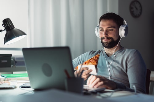 Man staying up late eating junk food and watching internet