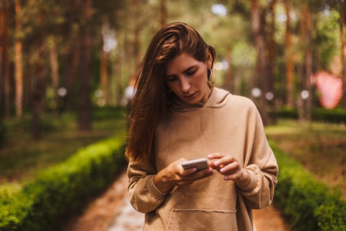 Woman checking phone during walk in park