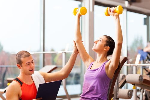 Trainer helping woman lift weights