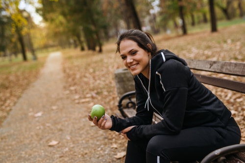Jogger sitting on park bench eating apple