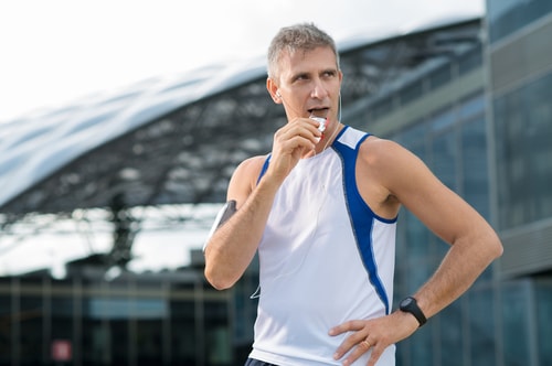 Jogger eating an energy bar in front of buildings